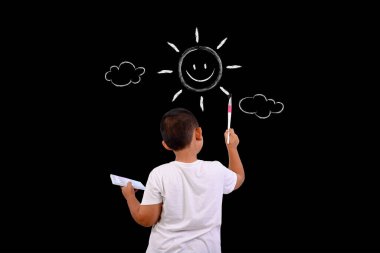 Bir çocuk gökyüzünü ve güneşi kara tahtayla çiziyor.