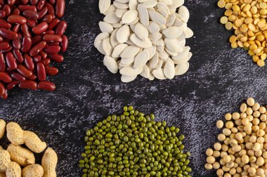Legumes, ve siyah çimento zemininde fasulye çeşitleri. Üst görünüm.