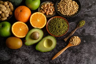 Siyah beton zemin üzerinde baklagiller ve meyveler.