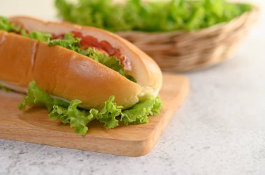 Ahşap kesme tahtasındaki Hotdog ve arkaplanı marul sepeti ile bulanıklaştırmış, boşluğu kopyala
