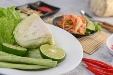 Lahana yeşili, limon, fasulye ve beyaz tabakta salata.