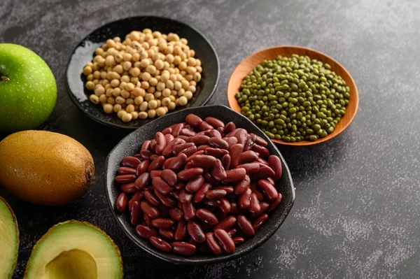 legumes and fruit on a black cement floor background.