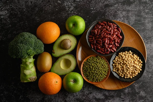 legumes and fruit on a black cement floor background.