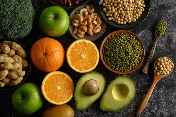 legumes and fruit on a black cement floor background.