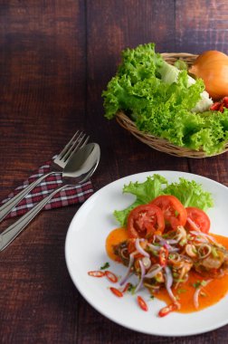 Dikey resim baharatlı sardalya salatası ile domates sosu karıştırılmış beyaz tabak ve kıvılcımlı paslanmaz kaşık ve peçetenin üzerinde çatal, ahşap masa üzerinde dokuma sepetinde yemek malzemesi, kopyalama alanı