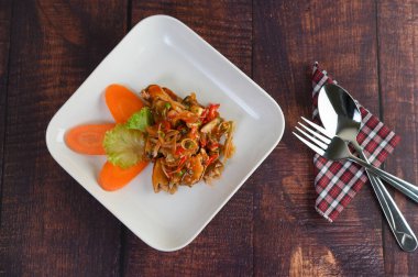 Baharatlı sardalya salatası, domates sosu, otla karıştırılmış beyaz tabak ve kıvılcımlı paslanmaz kaşık, peçetenin üzerinde çatal ve ahşap masada sepet içinde pişirme malzemesi, kopyalama alanı.