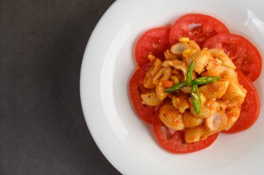 Üst görünüm ve kapalı boru rigate İtalyan makarna domates sosu ve yumurta, chili ve taze domates dilimi beyaz tabak, kopyalama alanı ve seçici odaklı