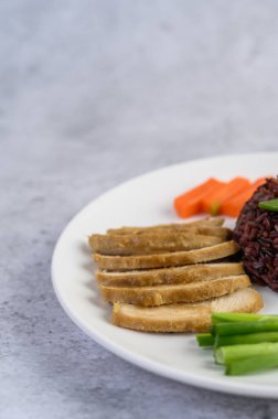 Balkabağı, bezelye, havuç, bebek mısır ve buharda pişirilmiş tavuk göğsü tabağında siyah pirinç..