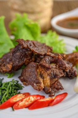 Beyaz bir tabakta kızarmış Tayland yemeği, taze soğan, kaffir limon yaprağı, biber, salata ve biber ezmesi. Seçici odak.