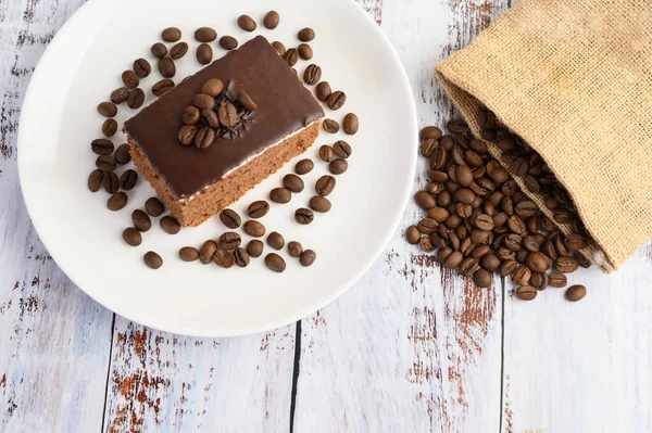 Chokladkaka Vit Tallrik Med Kaffebönor Ett Träbord Selektiv Inriktning — Stockfoto