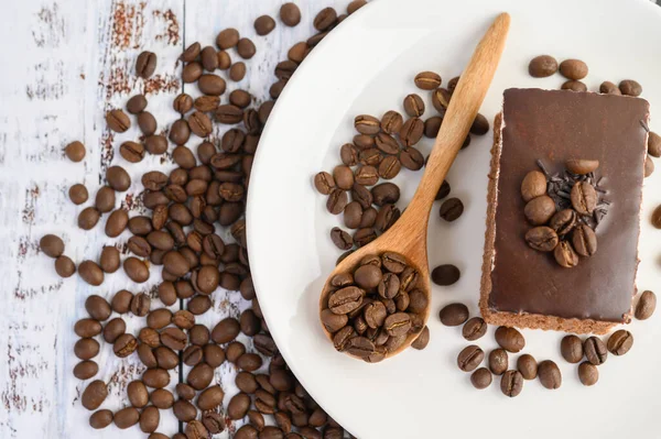 Chokladkaka Vit Tallrik Och Kaffebönor Träsked Ett Träbord — Stockfoto