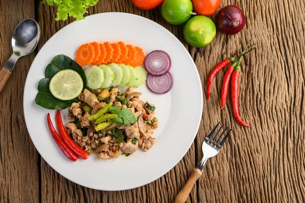 Stock image Spicy Minced Pork Salad on a white plate on wooden table. Top view.