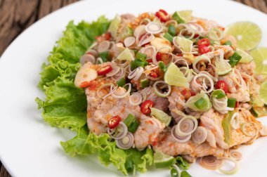 Baharatlı domuz salatası, galangal, limon, biber, sarımsak ve beyaz tabakta salata, ahşap masa..