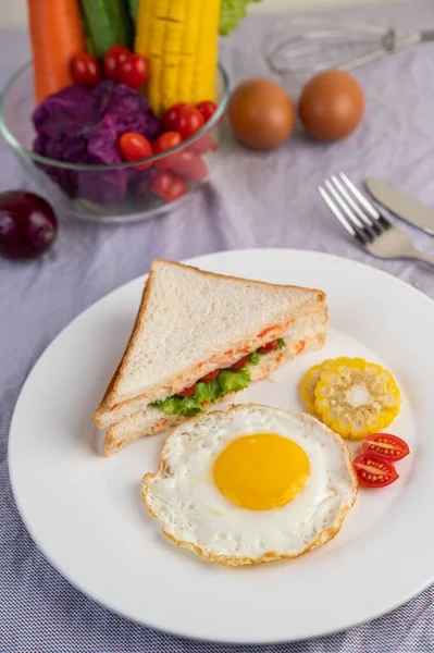 American breakfast on a white background with fried egg, salad, pumpkin, cucumber, carrot, corn, cauliflower, tomato and sandwich