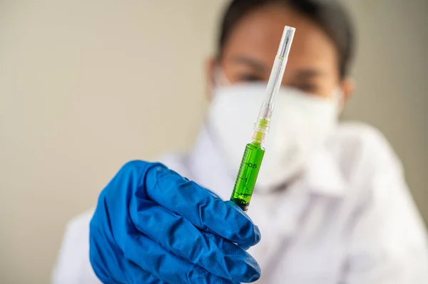 Scientists wearing masks and gloves Holding a syringe with a vaccine to prevent covid-19