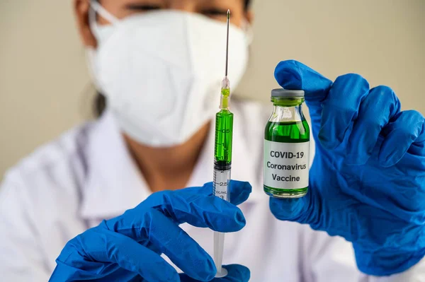 Scientists wearing masks and gloves Holding a syringe with a vaccine to prevent covid-19