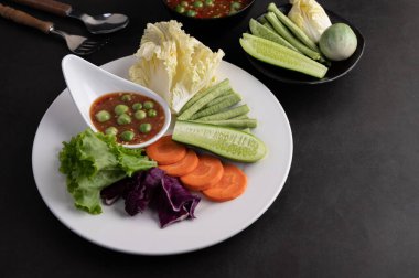Beyaz tabakta salatalık, fasulye, Tayland patlıcan, kızarmış beyaz lahana, havuç ve salatalı karides ezmesi sosu..