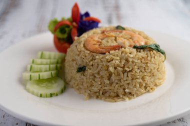 Domates ve salatalıktan oluşan beyaz bir tabakta karides pilavı..