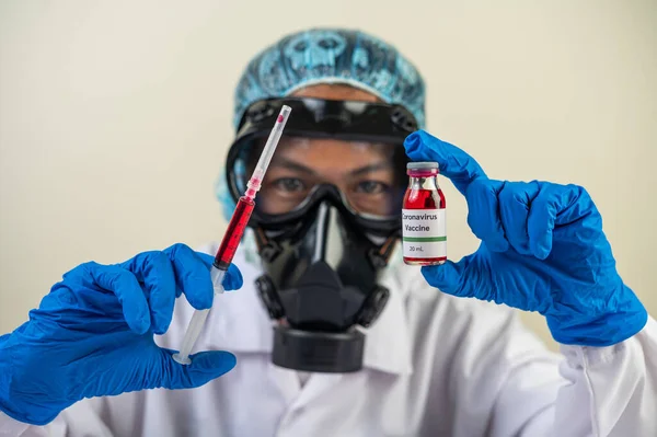 Scientists wearing masks and gloves Holding a syringe with a vaccine to prevent covid-19