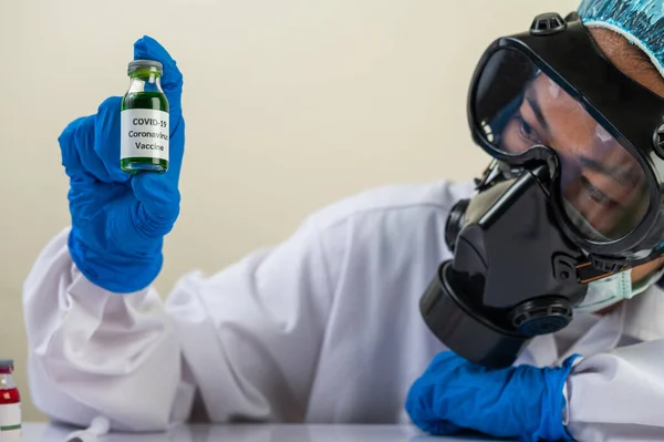 Scientists wearing masks and gloves, carrying vials with vaccines to protect Covid-19