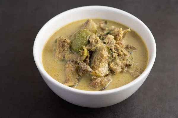 Chicken green curry in a white cup on the cement ground.