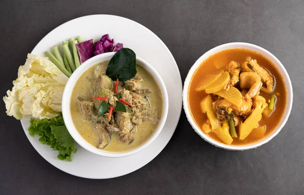 Chicken green curry in a white cup and Snakehead fish curry on the cement ground