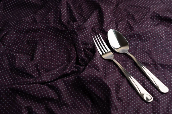 Spoon and fork placed on a wrinkled cloth. Selective foucs