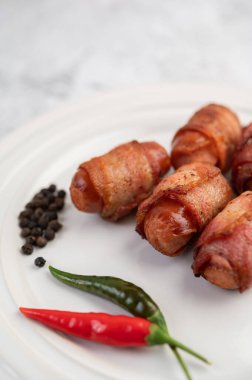 Beyaz tabakta sosis sarılı domuz göbeği. Seçici odak.