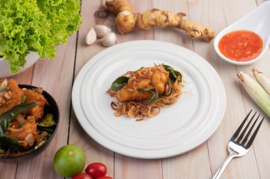 Beyaz tabakta kızarmış tavuk ve ahşap zeminde limon, sarımsak, limon ve domates sosu.