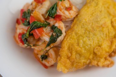 Beyaz tabakta karides ve omlet ile kaplı pirinç..