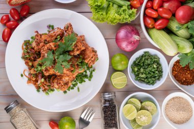 Salatalık, salatalık, marul ve ahşap masadaki garnitürle birlikte beyaz bir tabakta baharatlı tavuk..