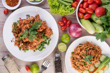 Salatalık, salatalık, marul ve ahşap masadaki garnitürle birlikte beyaz bir tabakta baharatlı tavuk..