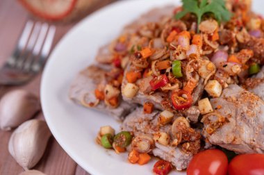 Domatesli baharatlı domuz eti ve ahşap bir masada beyaz bir tabakta marul. Seçici odak.