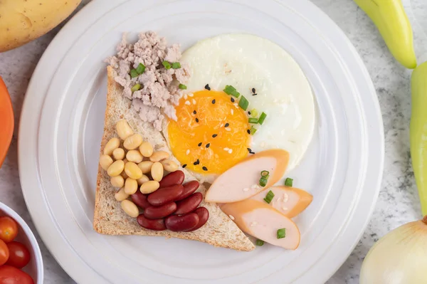 stock image Breakfast consists of fried eggs, sausage, minced pork, bread, red beans and soy on a white plate.