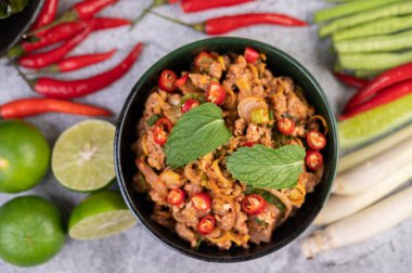 Limon, acı biber ve meze içeren siyah bir fincanda baharatlı domuz pirzolası. Seçici odak