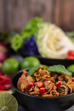 Limon, acı biber ve meze içeren siyah bir fincanda baharatlı domuz pirzolası. Seçici odak