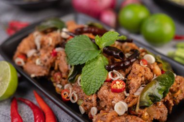 Limon, acı biber ve meze içeren siyah bir tabakta baharatlı domuz pirzolası. Seçici odak.