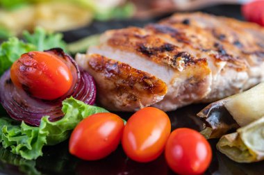 Siyah tabağa tavuk bifteği, dolma biber, domates, kırmızı soğan, ananas sosu, marul ve susam ekle..