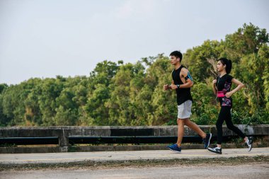 Erkekler ve kadınlar yolda koşarak egzersiz yaparlar..