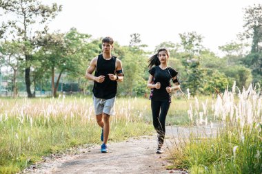 Erkekler ve kadınlar ağaçlar ve çiçeklerle sokaklarda koşuşturarak egzersiz yapıyorlar..