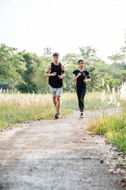 Erkekler ve kadınlar ağaçlar ve çiçeklerle sokaklarda koşuşturarak egzersiz yapıyorlar..