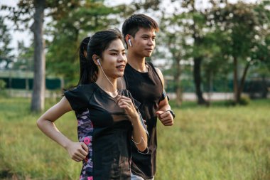 Erkekler ve kadınlar ağaçlar ve çiçeklerle sokaklarda koşuşturarak egzersiz yapıyorlar..