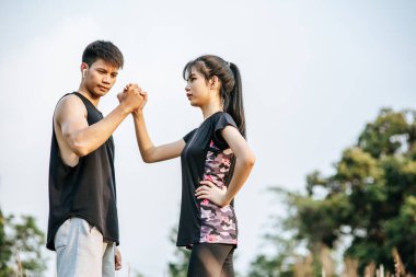 Kadınlar ve erkekler egzersiz yapmak için el ele tutuşuyorlar..