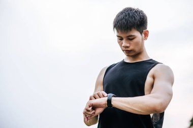 Siyahlı adam ayağa kalkar ve bileğini izler. Seçici odak.