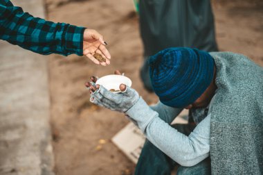 Beze sarılmış dilenciler ve sonra bir şapka takıp caddenin kenarına oturdular ve biri para verdi..