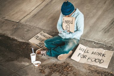 Dilenciler köprünün altında bir tabelayla oturuyorlar, lütfen eve dönün..