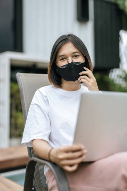 Havuz başında maske takan ve dizüstü bilgisayar oynayan kadınlar. Seçici odak.