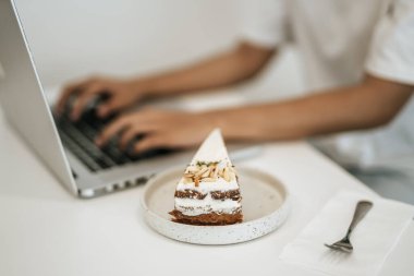 Kek tabakta, dizüstü bilgisayarla oynayan kişinin yanında. Seçici odak.