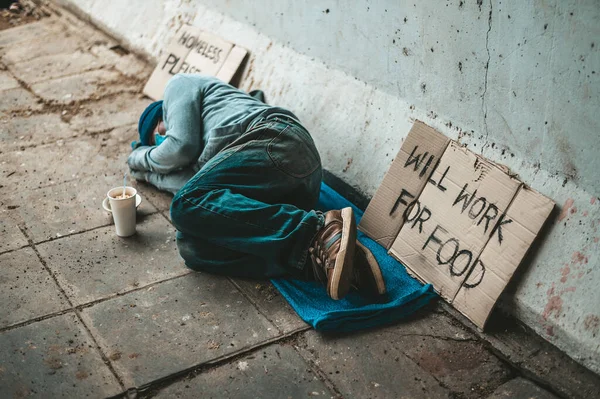 The beggars lay on their side of the street with dirty clothes.