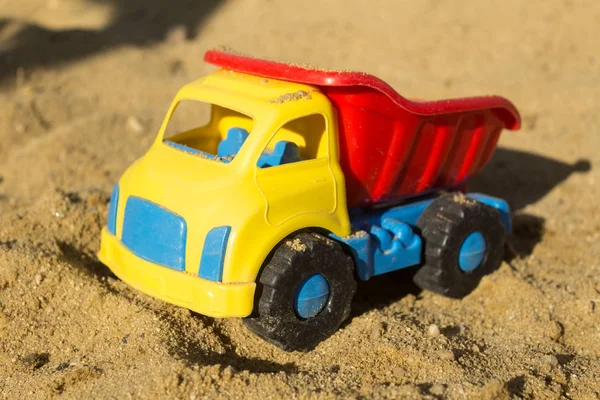 Żółty, czerwony i niebieski ciężarówka zabawka w piasku na plaży. Zabawki dla chłopców — Zdjęcie stockowe